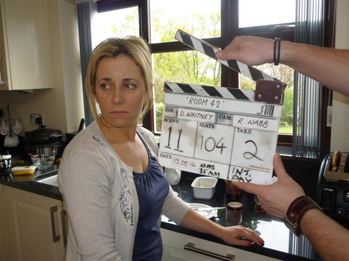 Room 42 clapperboard and cast member